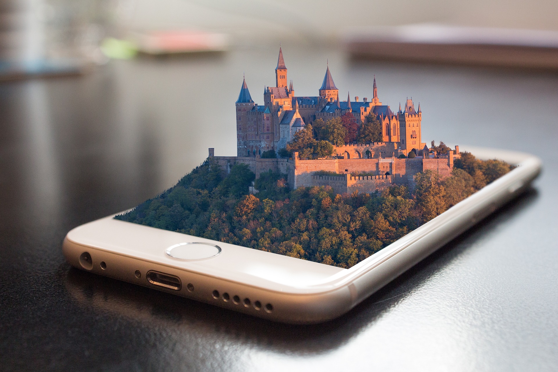 Celular sobre a mesa com um castelo medieval 3D saindo da tela. Trazendo a ideia de que Dicas de Segurança Digital criam uma fortaleza em seu dispositivo.